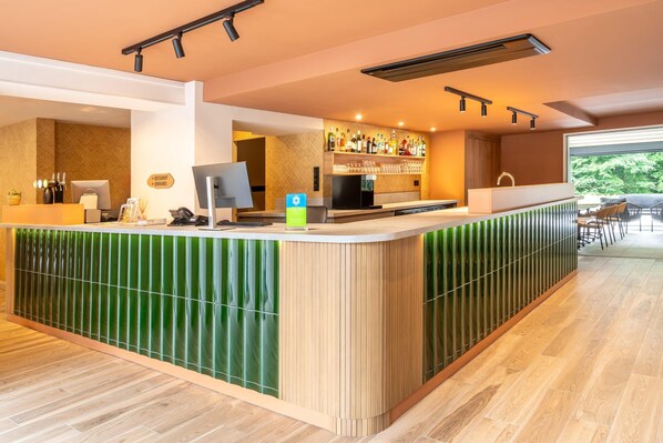 A modern bar area with a counter, bar stools, and a large window offering a view of the outdoors.