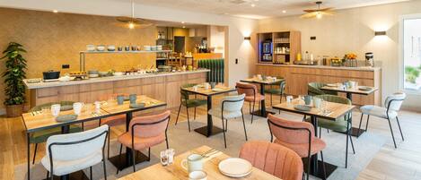 A modern dining area with multiple tables and chairs, a bar area, and a kitchen visible in the background.