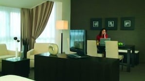Een hotelkamer met een bed, een bureau, een stoel, een lamp en een televisie.