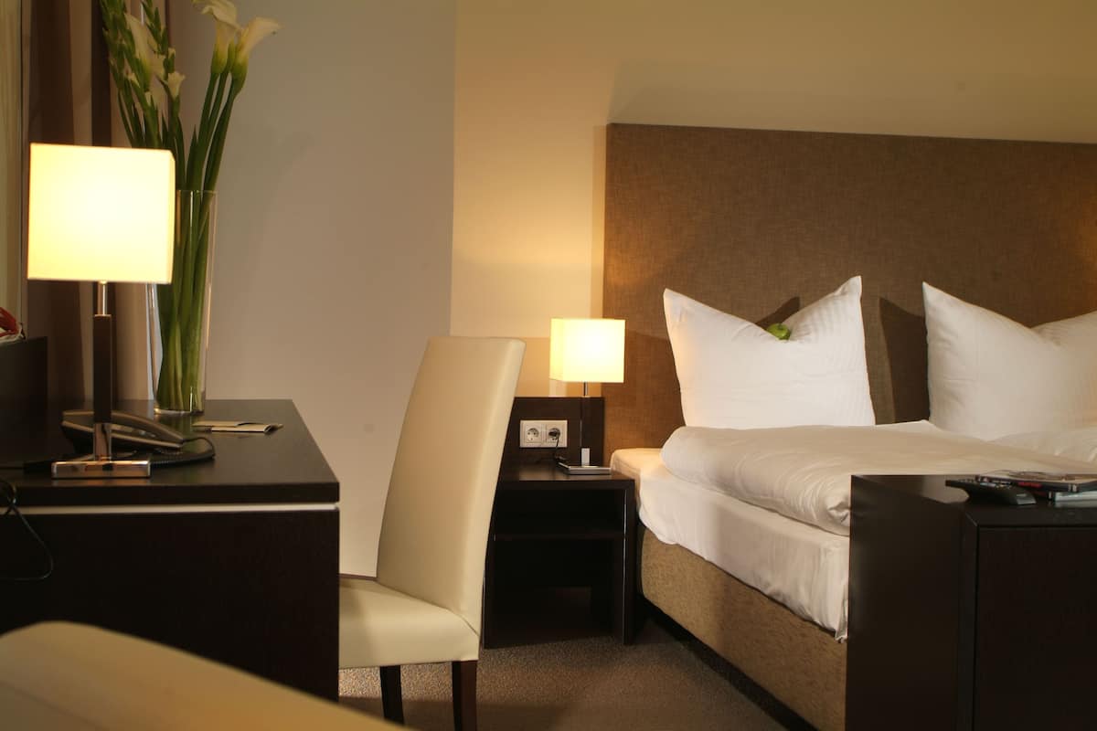 Ein Hotelzimmer mit Bett, Nachttischen, Schreibtisch, Stuhl und Lampe.