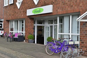 Ein Hotel namens 'Friends' mit Ziegelaußenwand, Außenbereich zum Sitzen und einem Bereich zur Fahrradabstellung.