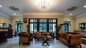 A spacious lobby with a chandelier, large windows, and two sofas. - Hotel Grand Sal (Wieliczka)