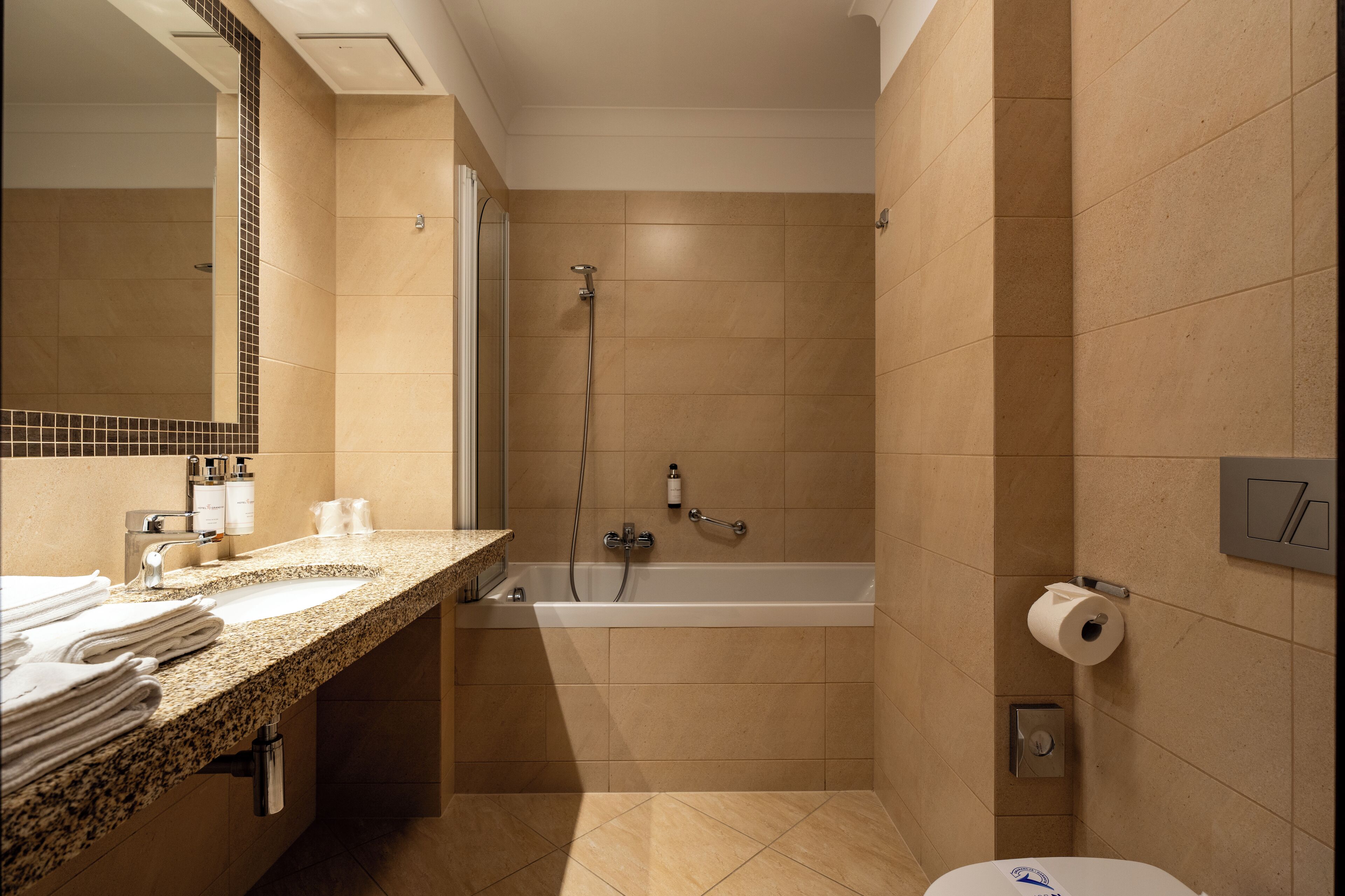 Un baño con lavamanos, espejo, toallero, ducha e inodoro.