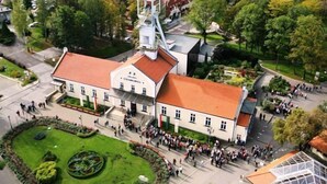 A large building with a red-tiled roof, surrounded by a well-maintained lawn and a circular garden. - Hotel Grand Sal (Wieliczka)