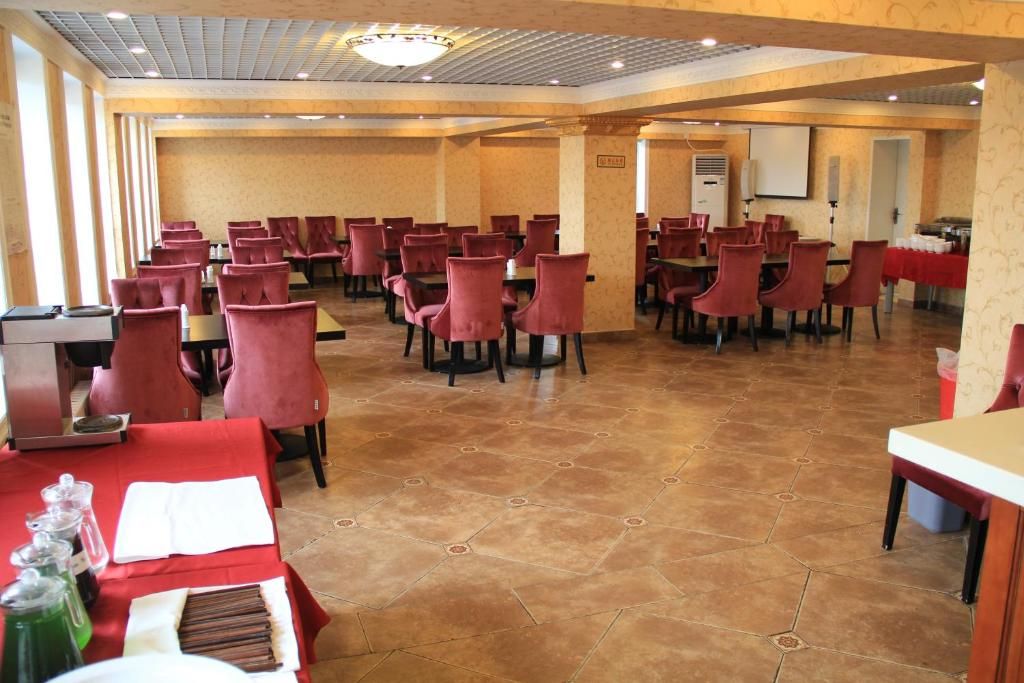 A conference room with rows of red chairs, a podium, and a buffet table.