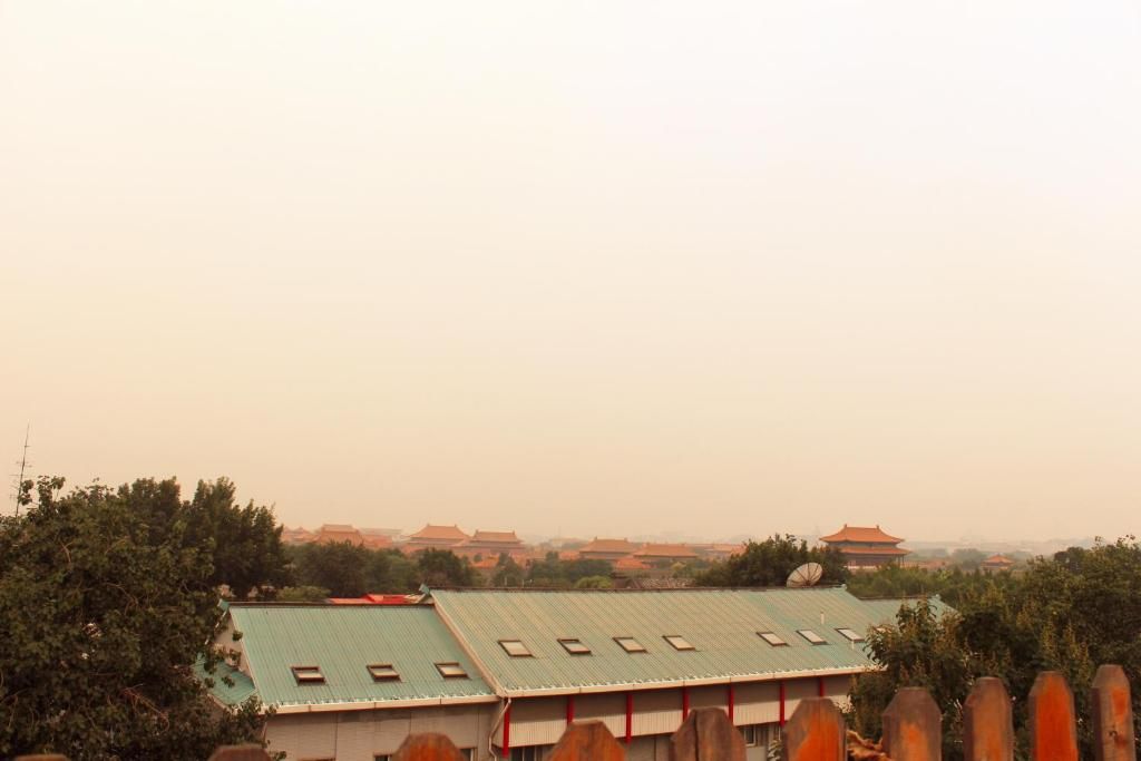 A building with a green roof and multiple windows, surrounded by trees and other buildings in the background.