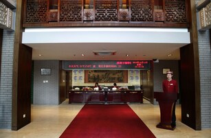 A reception area with a red carpet, a reception desk, and a large framed painting on the wall.