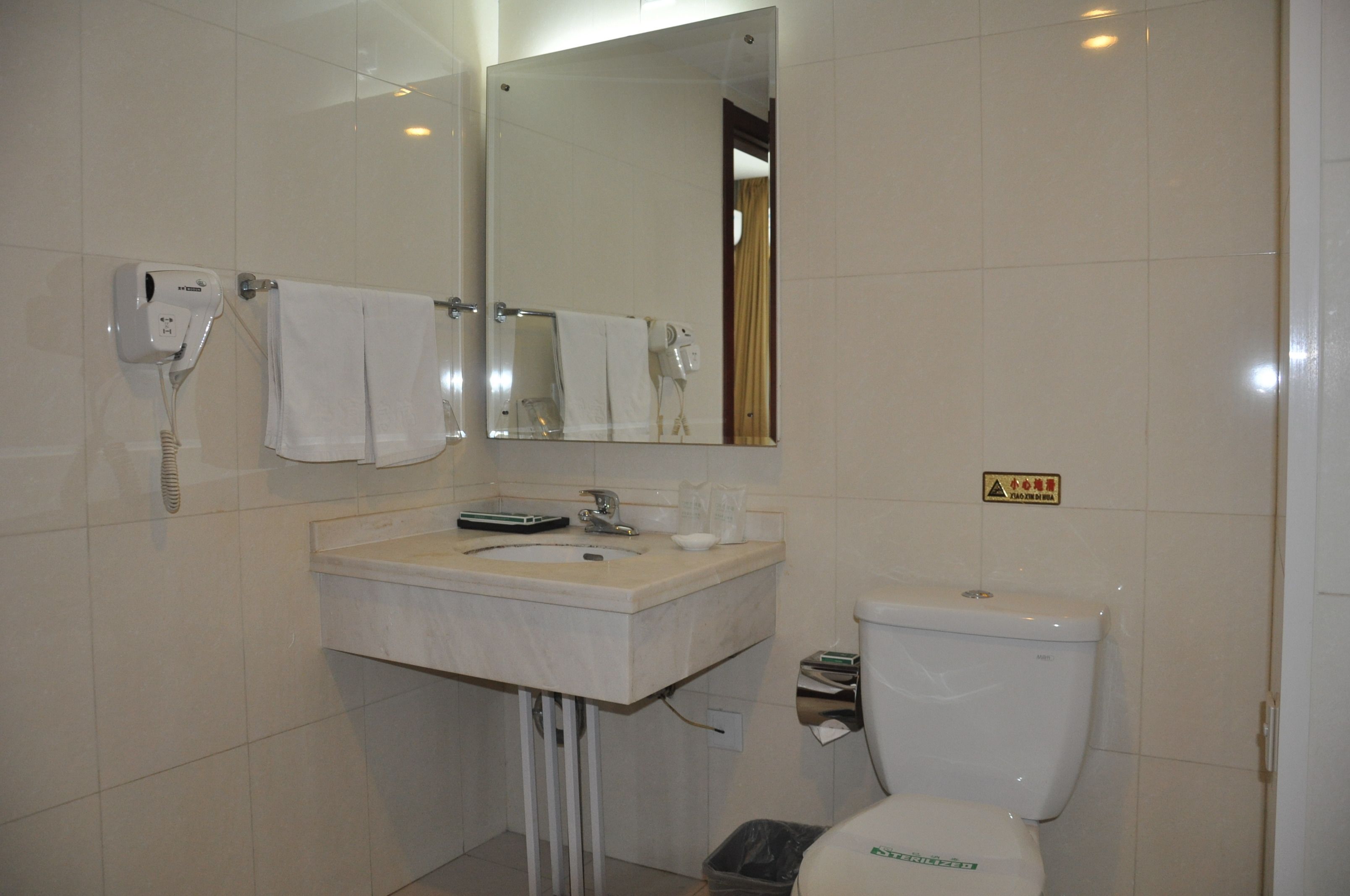 Un baño con lavamanos, espejo, toallero y retrete.