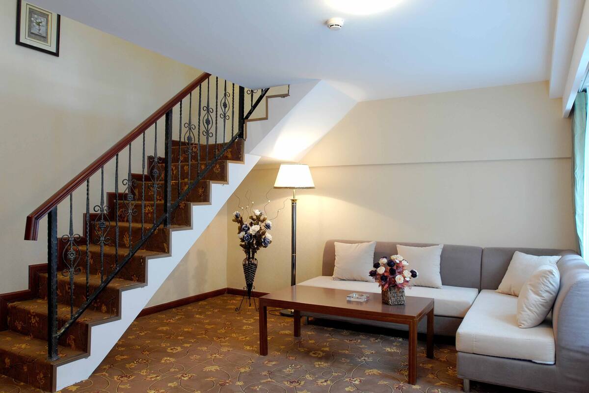 A staircase with ornate railings, a sofa, a coffee table, and a lamp in a living room.