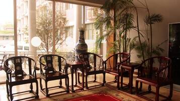 A room with a large window, a red patterned rug, and several wooden chairs.