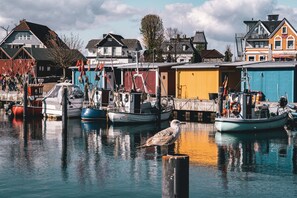 A harbor with boats docked, a seagull on a post, and houses in the background. - Hotel Gran BelVeder & Ostsee Therme Resort & Spa (Scharbeutz)