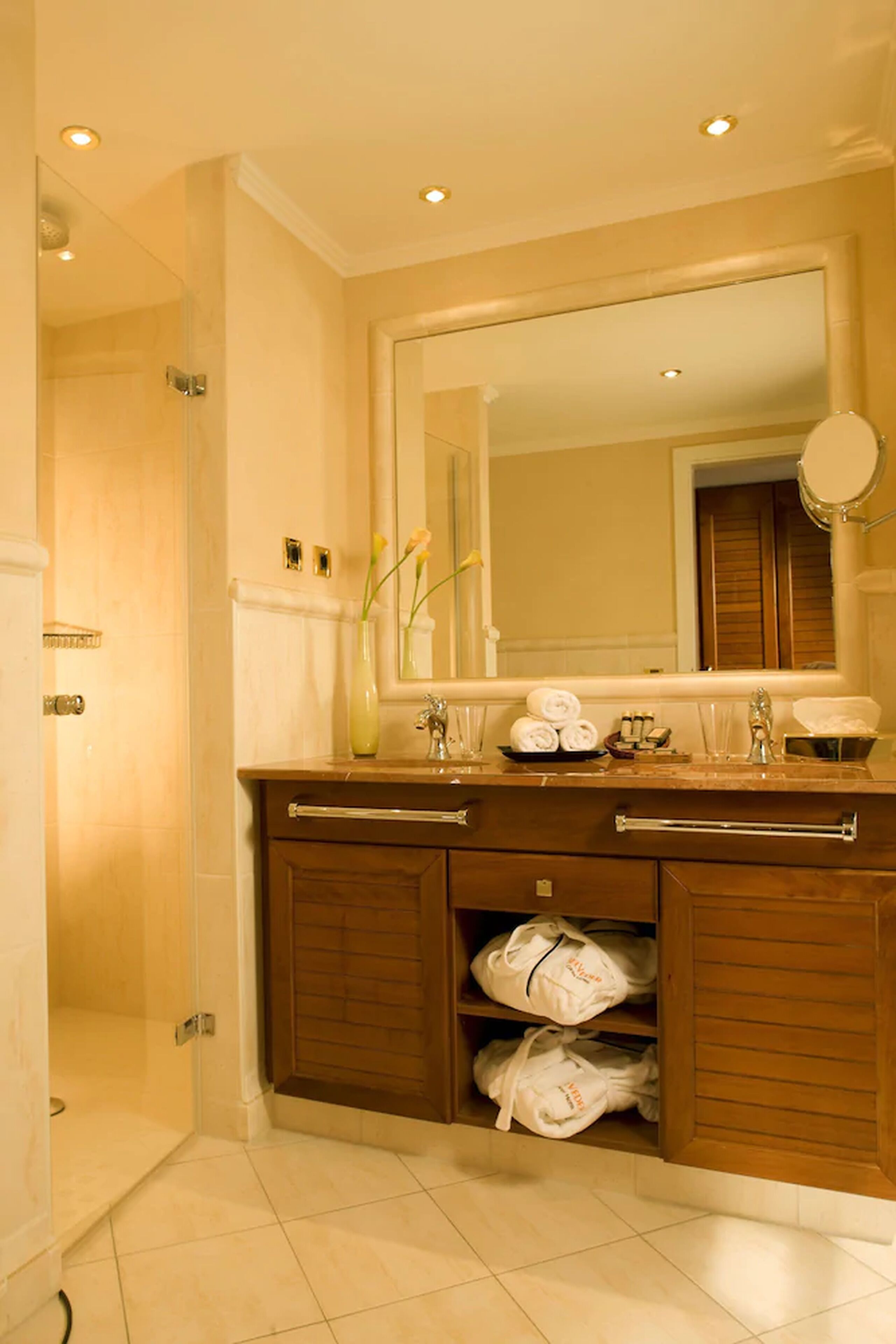 A modern bathroom with a large mirror, a vanity with a sink, and a shower area.