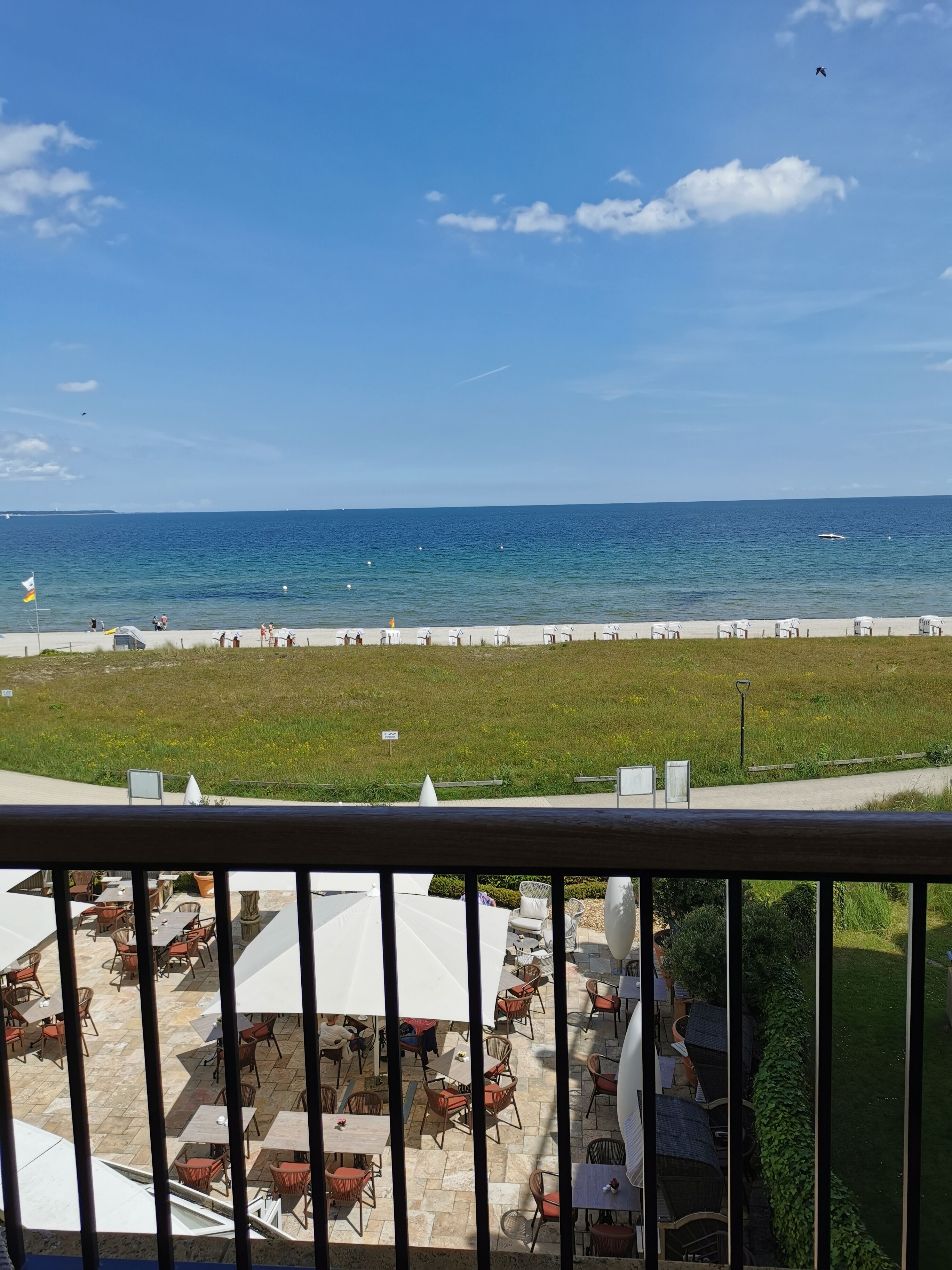 Une vue sur la mer depuis un balcon, avec un espace salon extérieur et une vue sur la plage et l’océan.