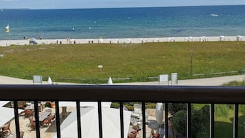 Une vue sur la mer depuis un balcon, avec un espace salon extérieur et une vue sur la plage et l’océan.