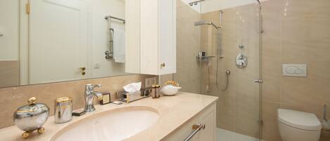 Un baño moderno con un lavamanos grande, una ducha con cerramiento de vidrio y un inodoro.