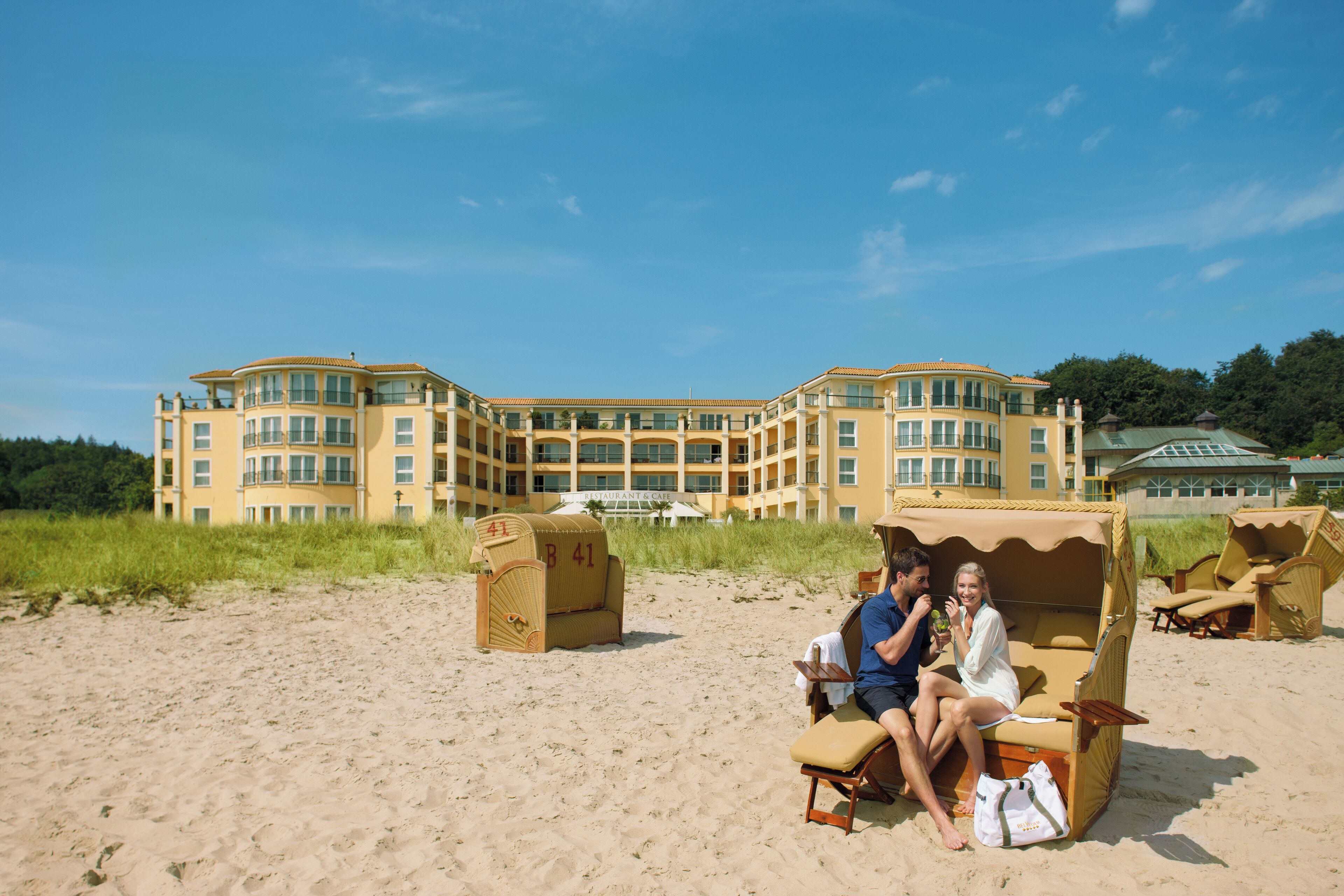 A beachfront hotel with multiple balconies, beach chairs, and a sandy beach.
