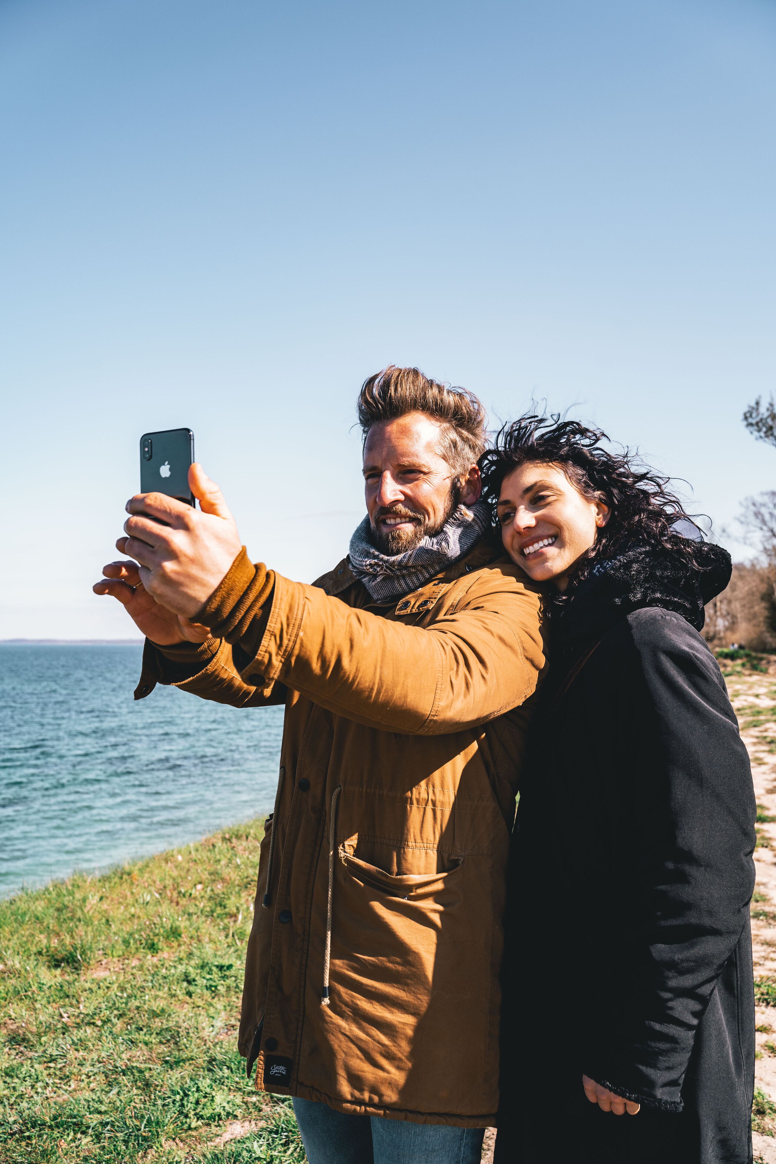 Ein Paar macht ein Selfie am Wasser.