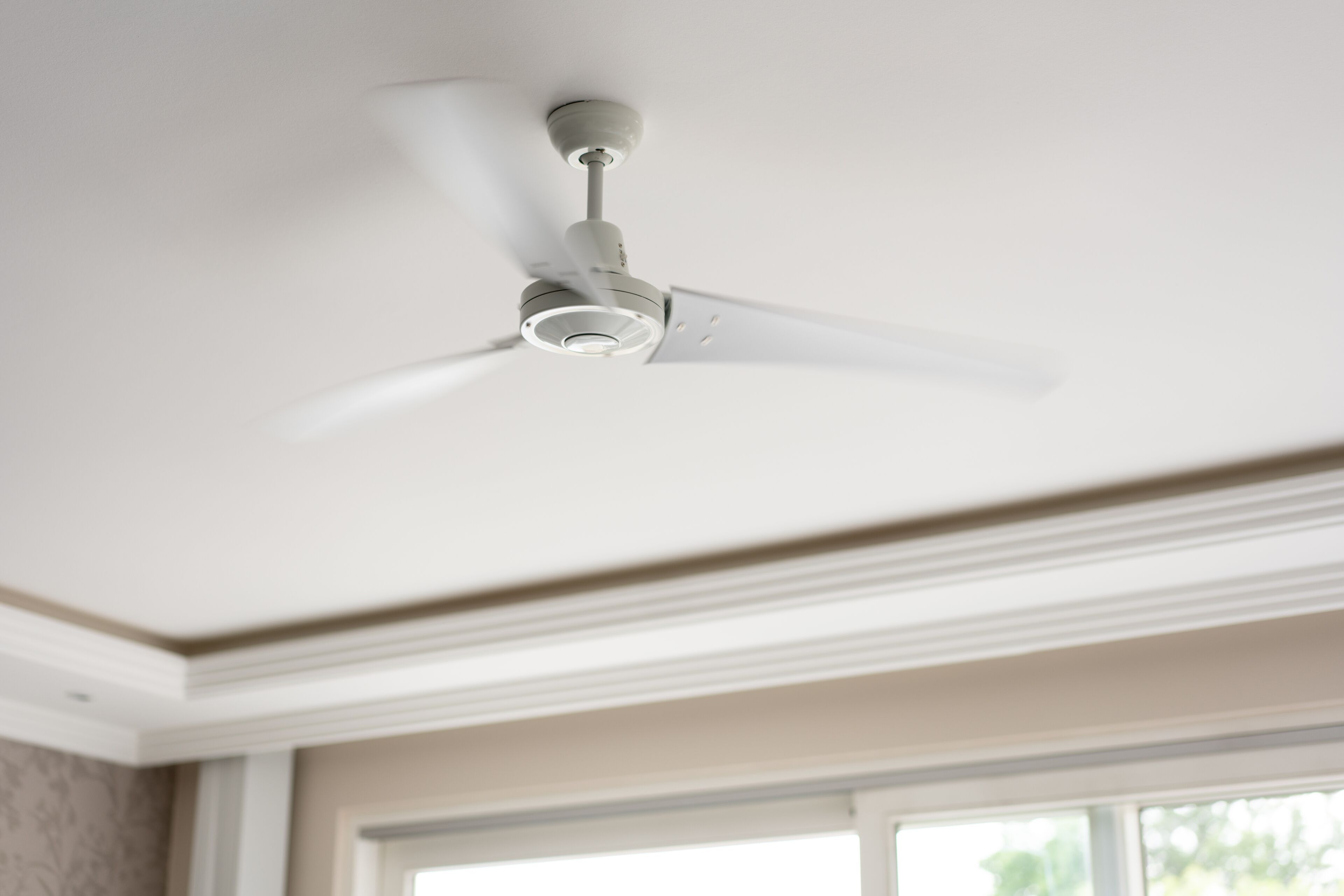 A ceiling fan in a room with a window.