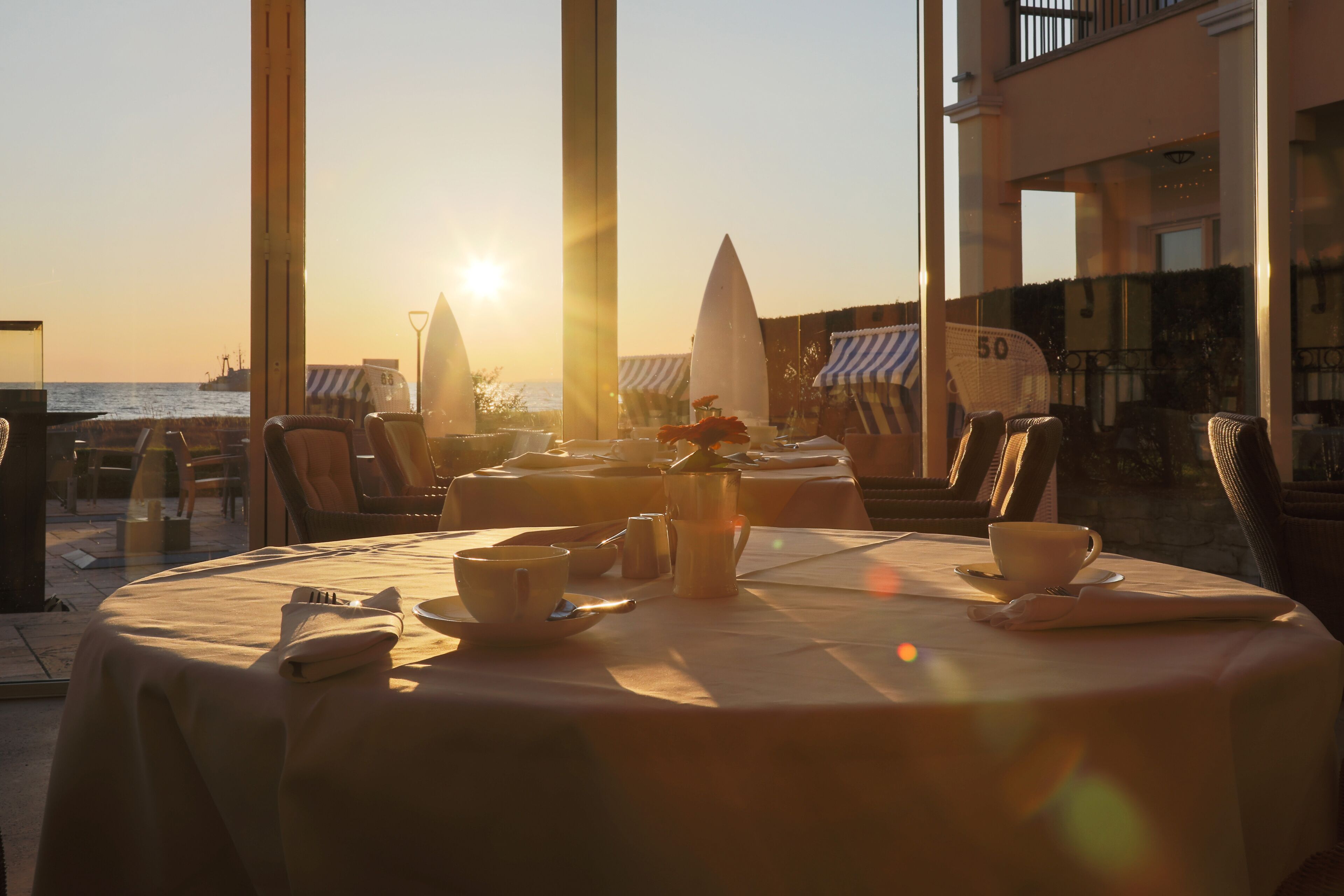A table set for two with a view of the sea and a sunset.