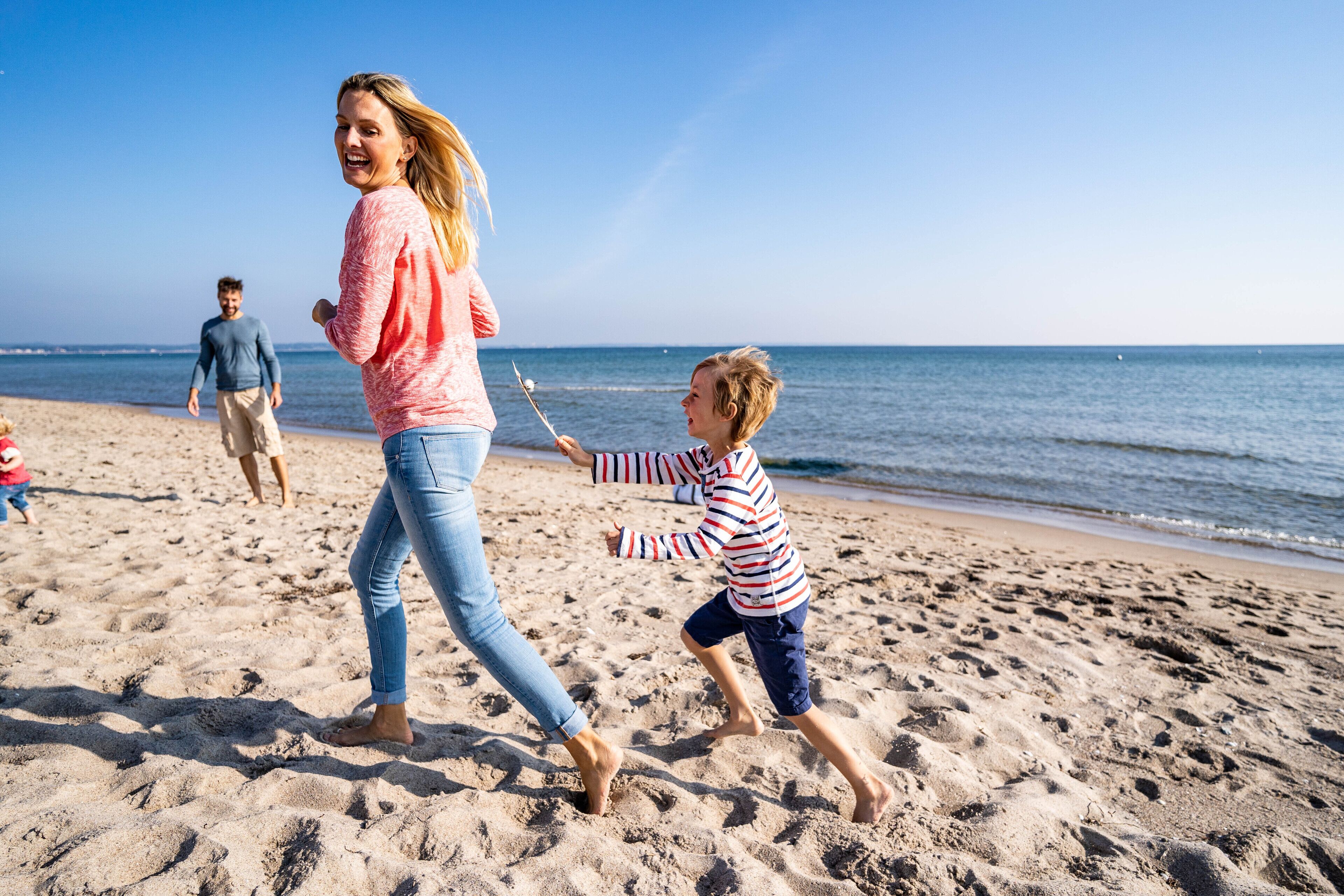 Ein Sandstrand mit Menschen, die spazieren gehen und spielen.