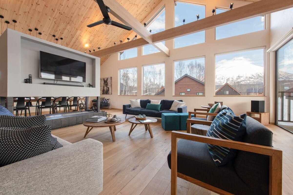 A spacious living area with a high ceiling, large windows, and a modern interior design.