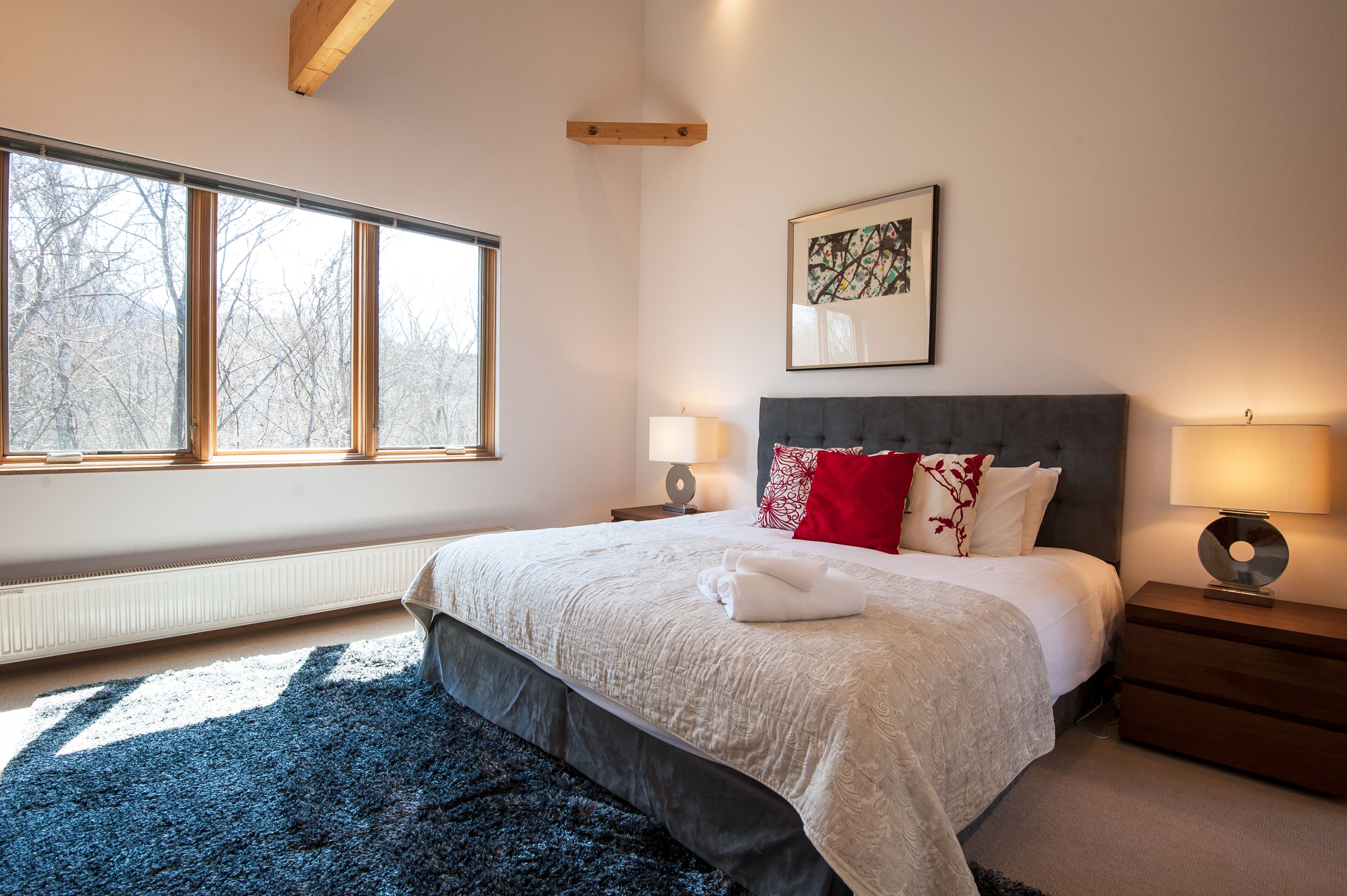 Een slaapkamer met een groot bed, twee nachtkastjes, een raam en een radiator.