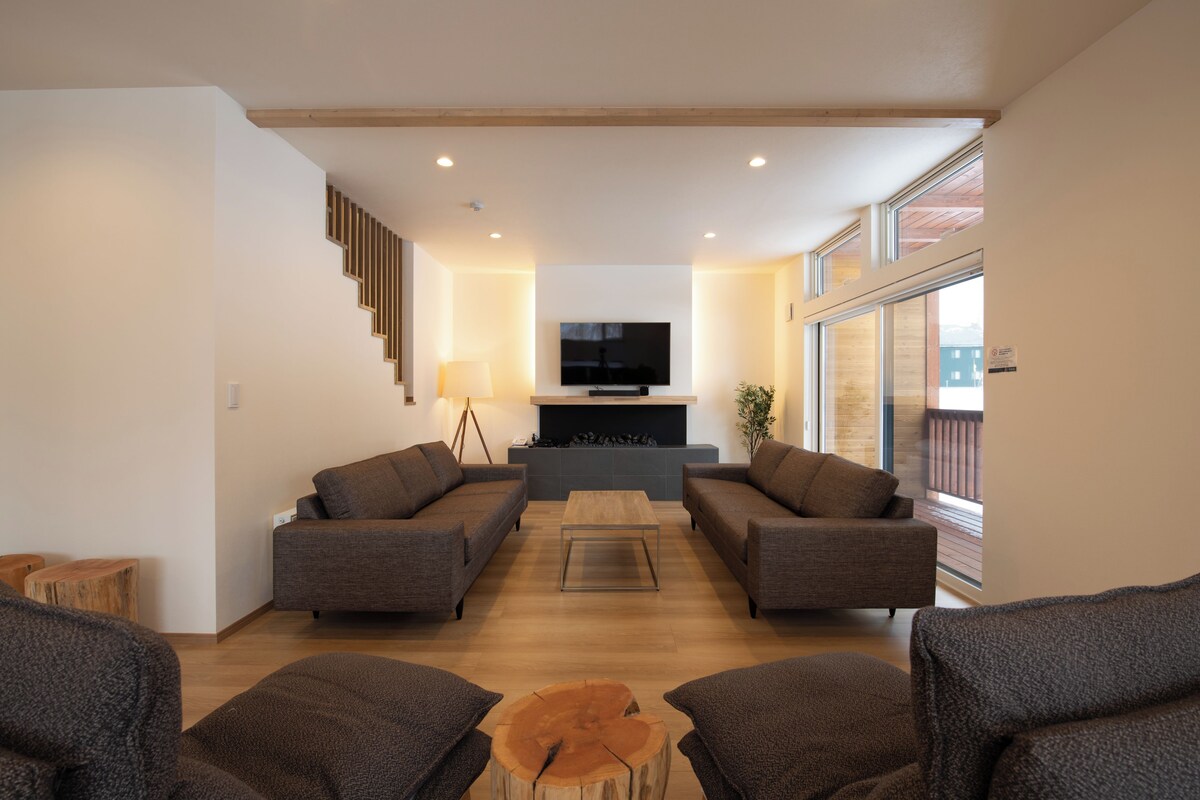 A modern living room with a fireplace, two sofas, a coffee table, and a TV.