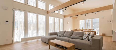 Un salón espacioso con un sofá modular grande, una mesa de centro de madera y un comedor con mesa y sillas.