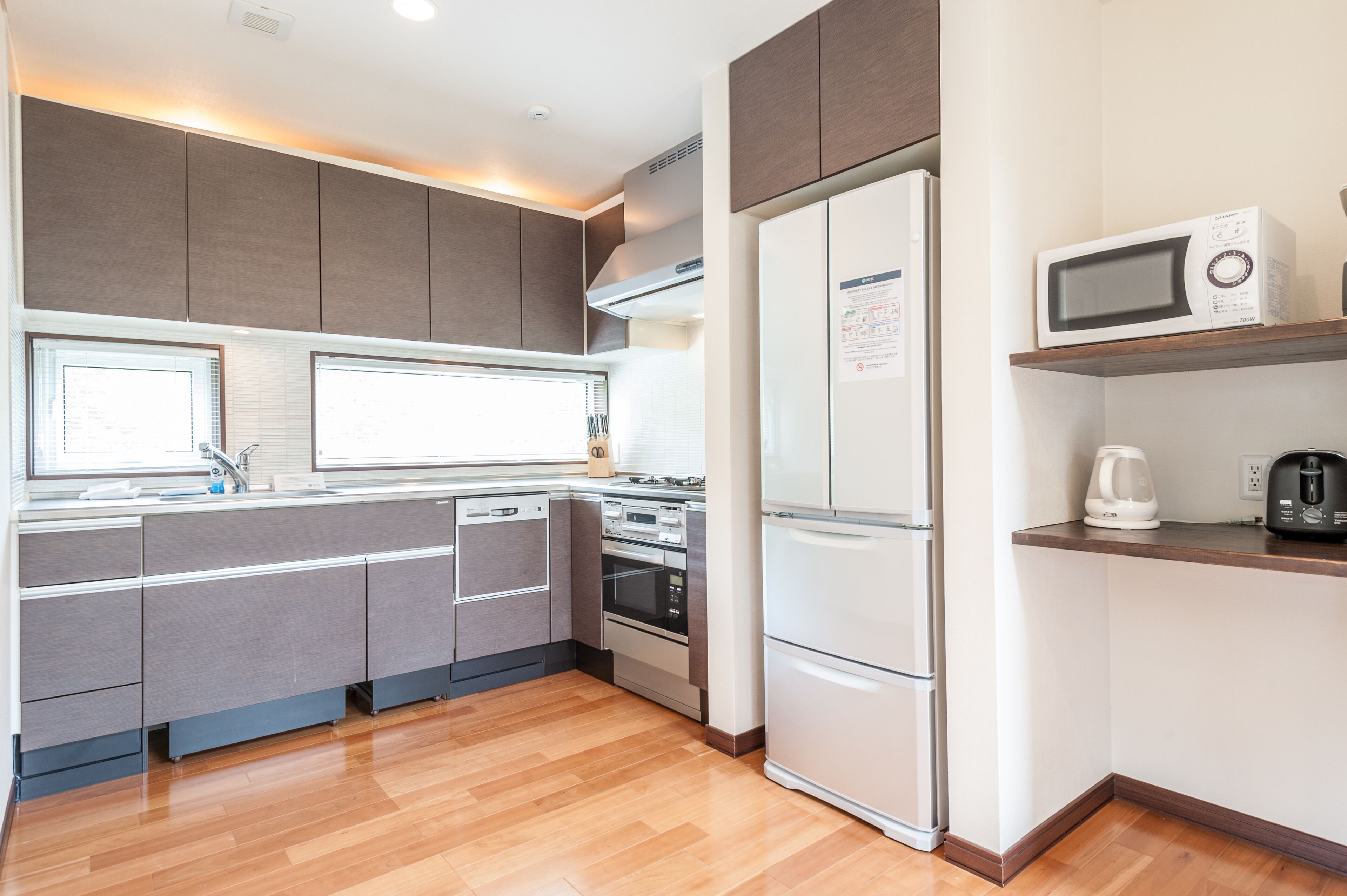 A modern kitchen with grey cabinets, a stainless steel refrigerator, a microwave, and a coffee maker on a wooden countertop.