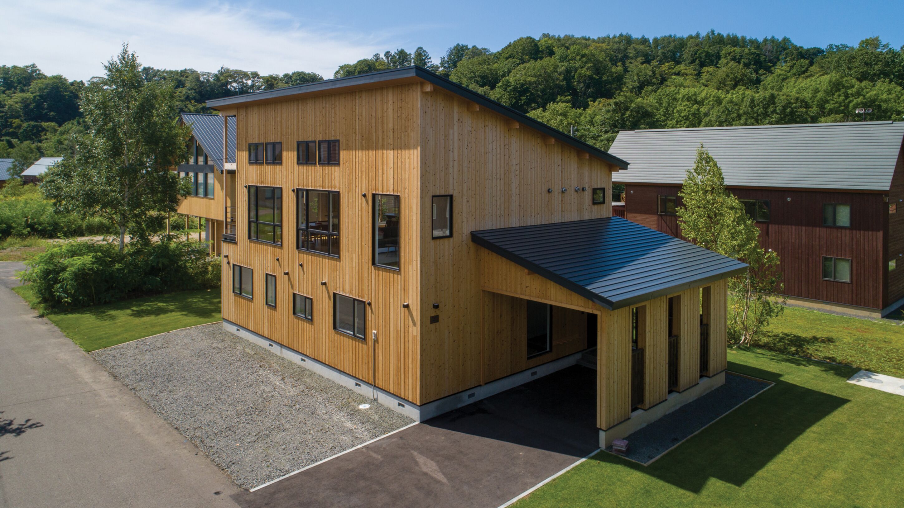 A modern wooden building with multiple windows and a covered entrance.