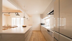 A modern kitchen with a central island, wooden flooring, and stainless steel appliances. - Country Resort Niseko (Kutchan)