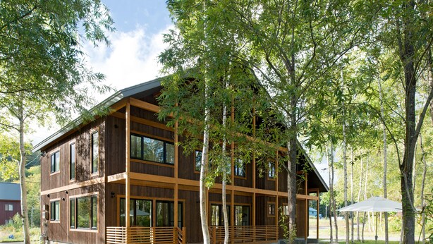 A two-story wooden cabin with large windows, a wooden deck, and a dining area with outdoor furniture. - Country Resort Niseko (Kutchan)