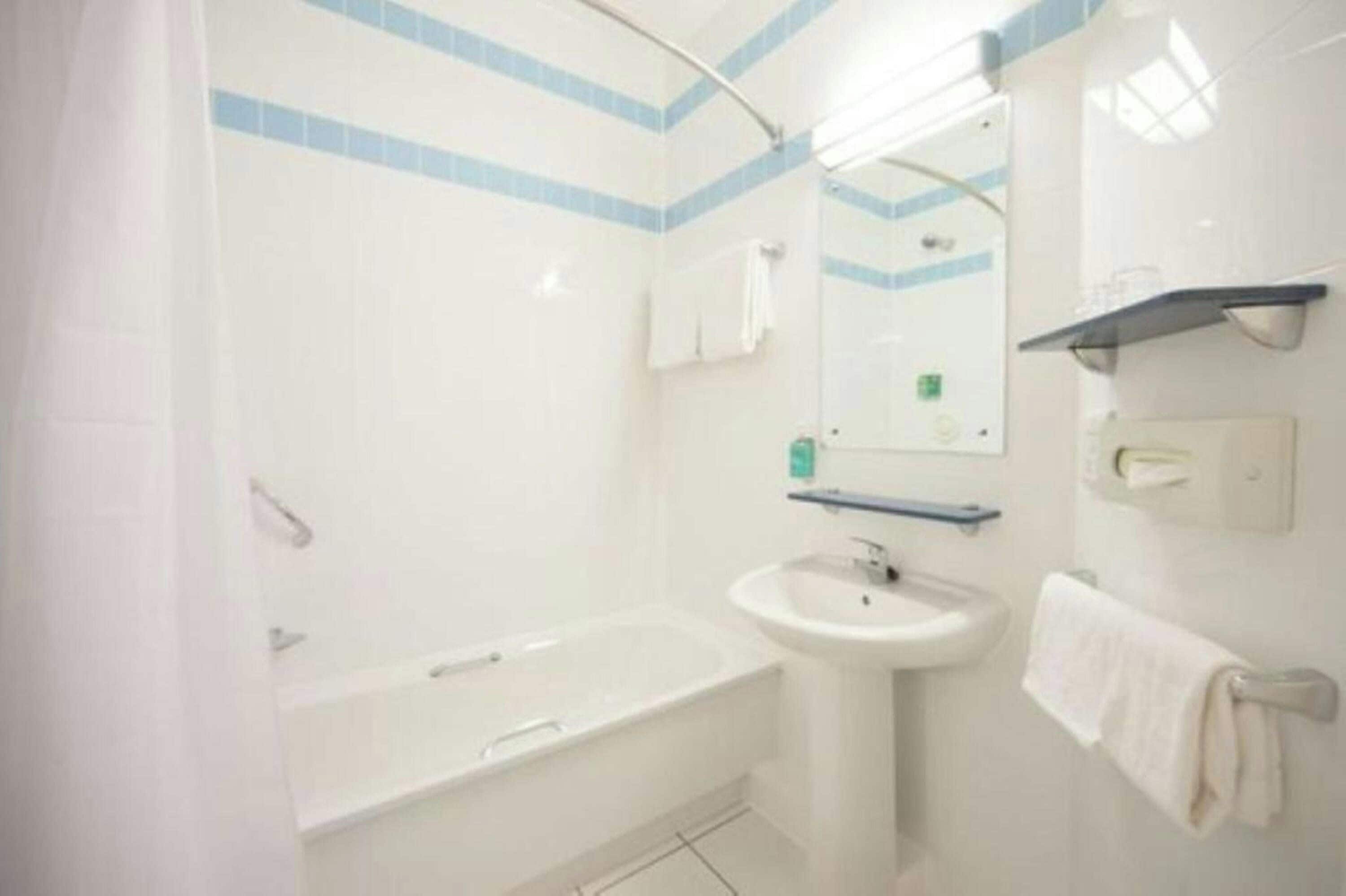 Un baño con bañera, lavabo y espejo.