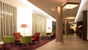 A hotel lobby with seating areas, a reception desk, and a patterned carpet.