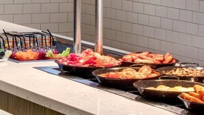 A buffet counter with various food items and utensils.