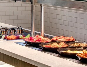 A buffet counter with various food items and utensils.