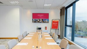 Ett konferensrum med ett långt bord, stolar, en projektorduk och utsikt över omgivningarna.