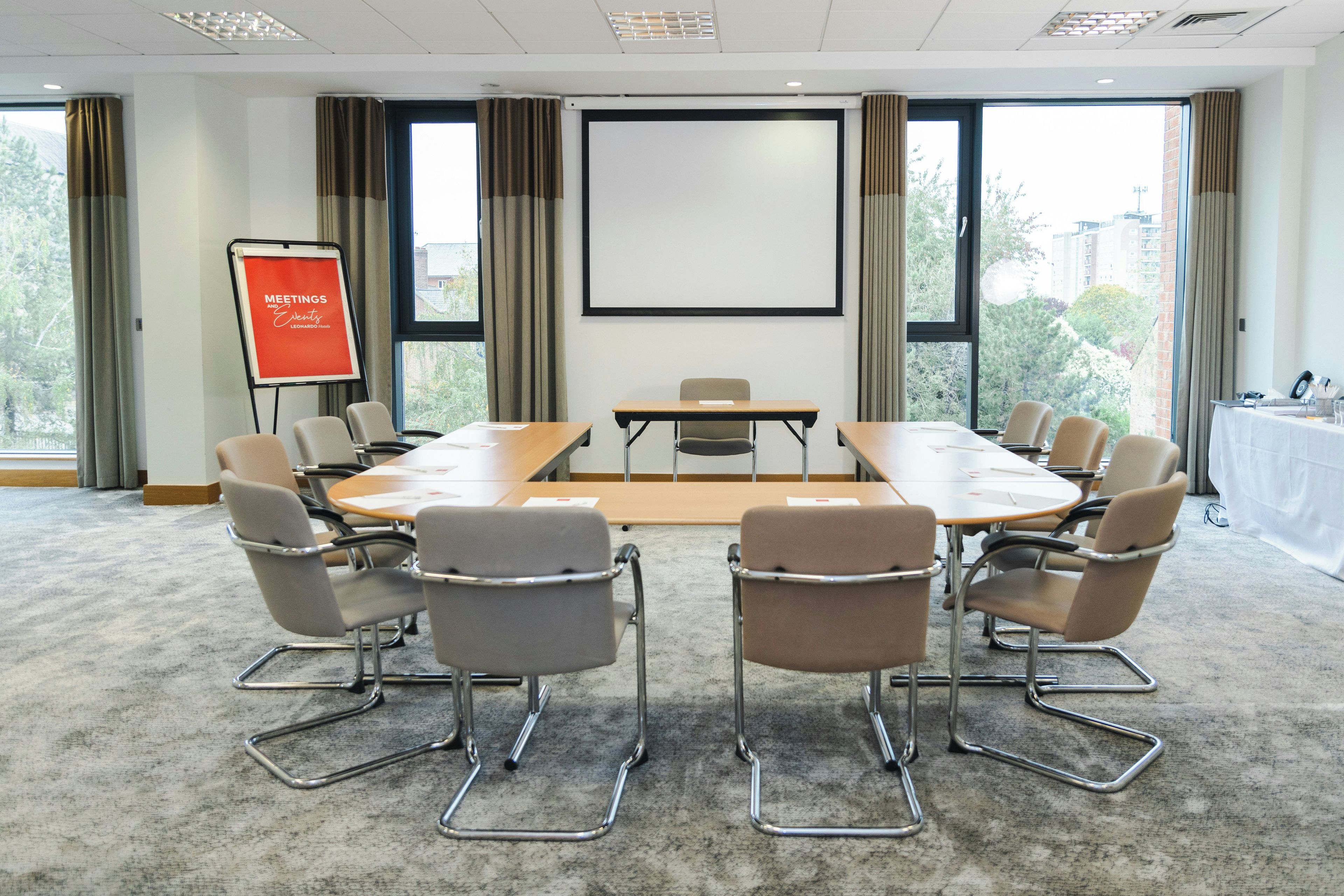 A conference room with a large table, chairs, a projector screen, and a whiteboard.