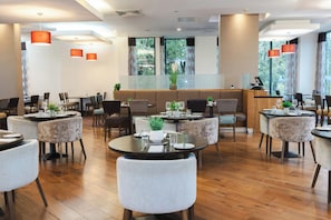 A restaurant with round tables, chairs, and a bar area. - Leonardo Hotel Derby (Derby)