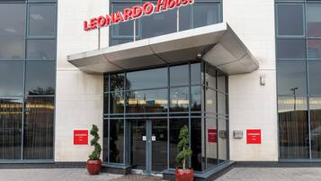 Exterior del Hotel Leonard, con un diseño moderno, destacando amplios ventanales y un llamativo letrero rojo.