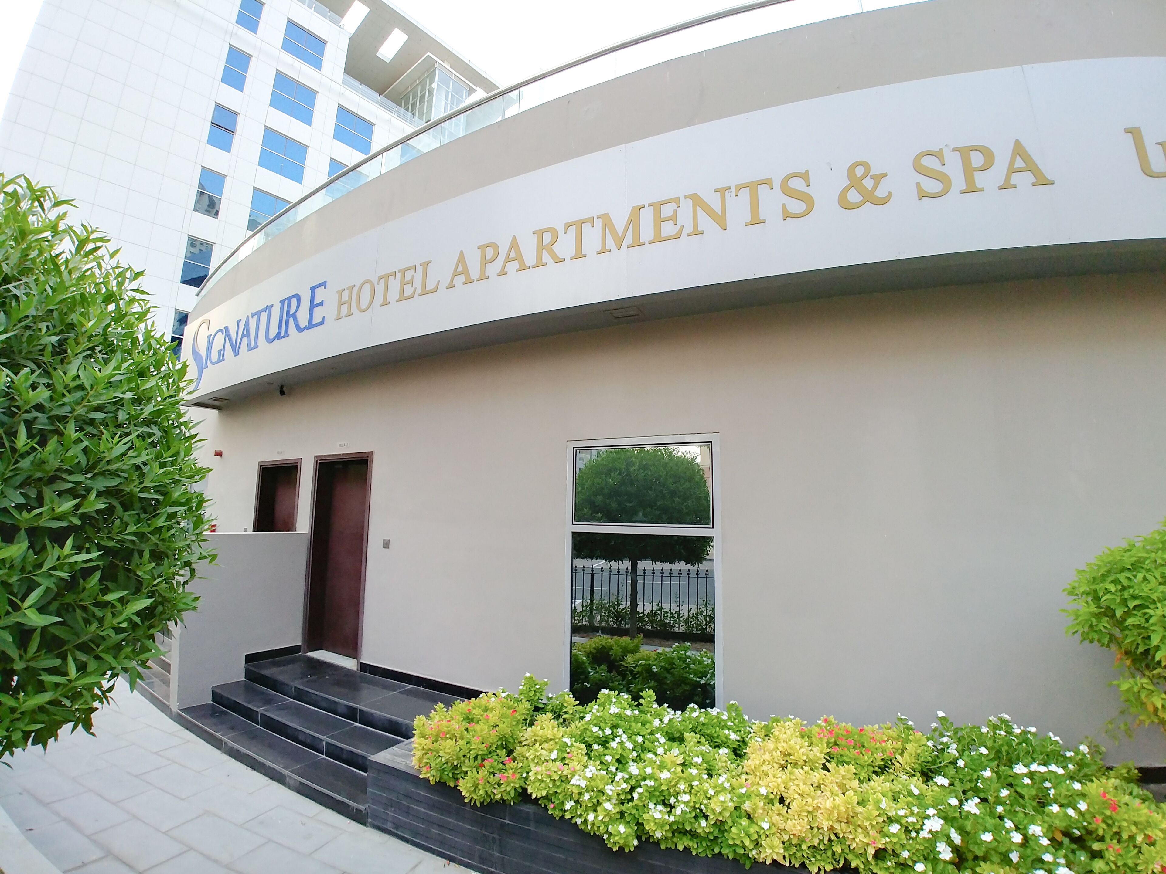 Entrada de un hotel con un cartel que dice 'Signature Hotel Apartments & Spa'.