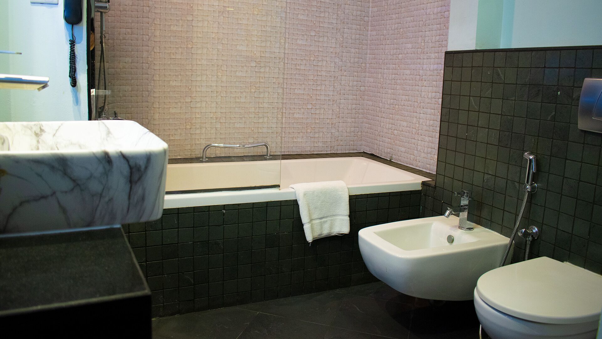 Un baño con lavamanos de mármol, bañera, bidé e inodoro.