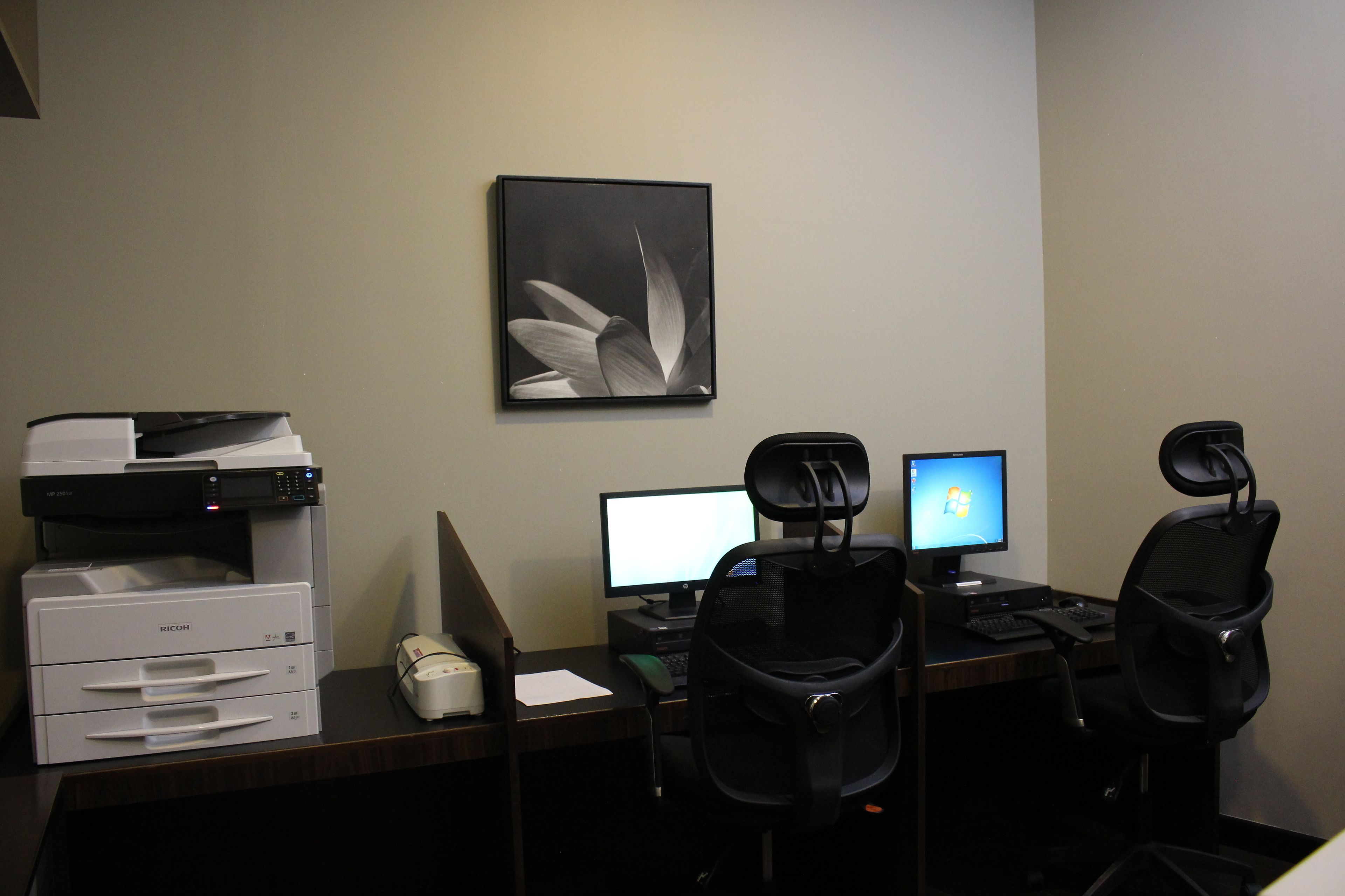 A workspace with two computers, a printer, and office chairs.