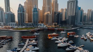 A marina with various boats docked, surrounded by high-rise buildings.