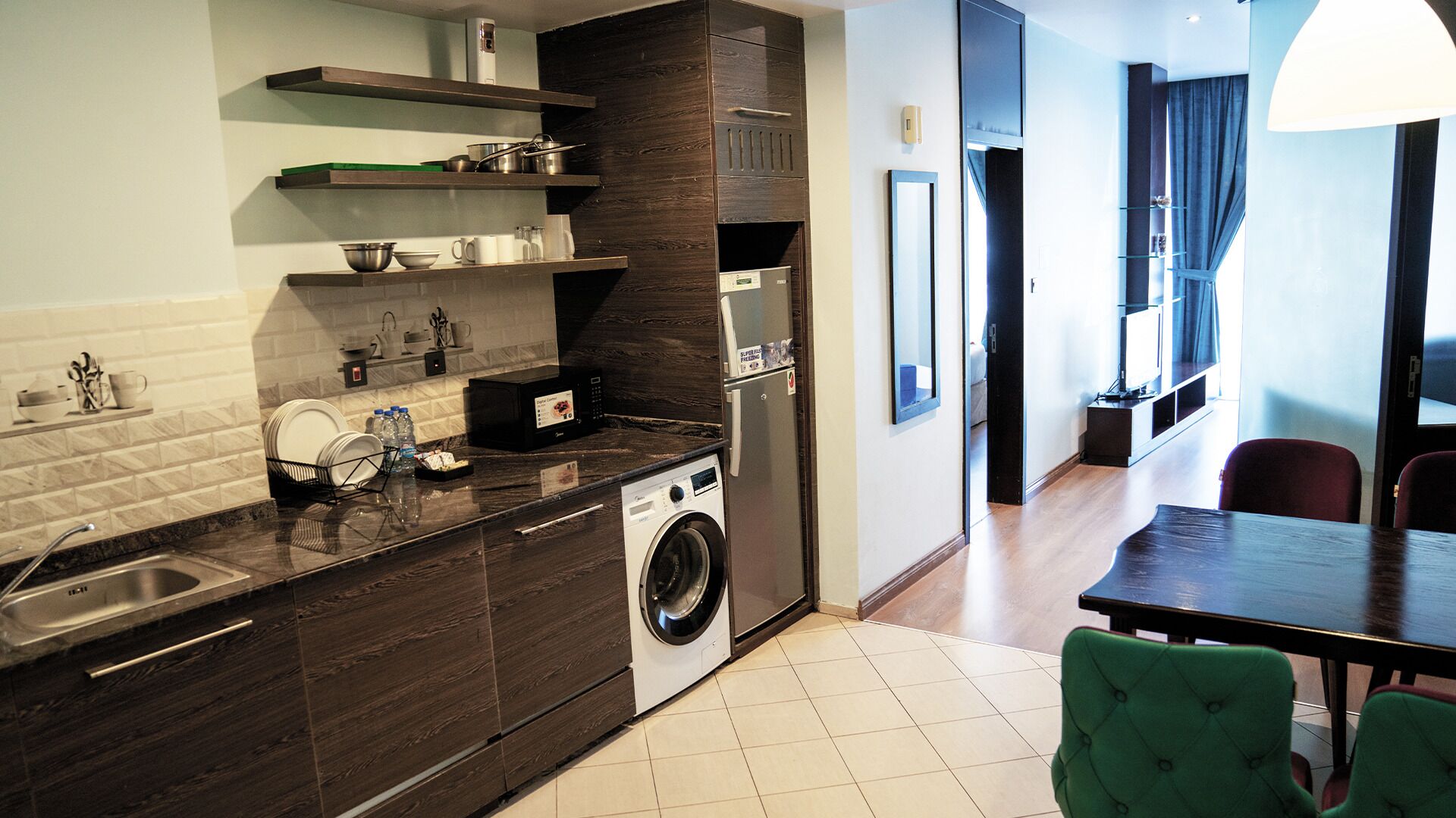A compact kitchen with a washing machine, a sink, and a dining area with a table and chairs.