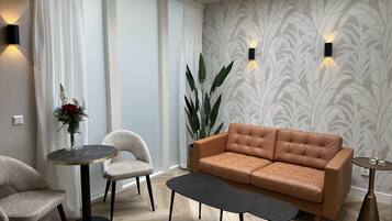 A modern living room with a leather sofa, two chairs, a coffee table, and a potted plant.