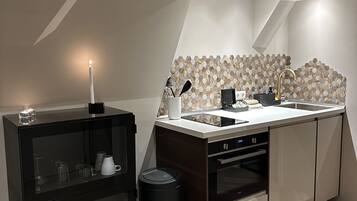 A modern kitchen with a built-in oven, a sink with a gold faucet, and a hexagonal tile backsplash.