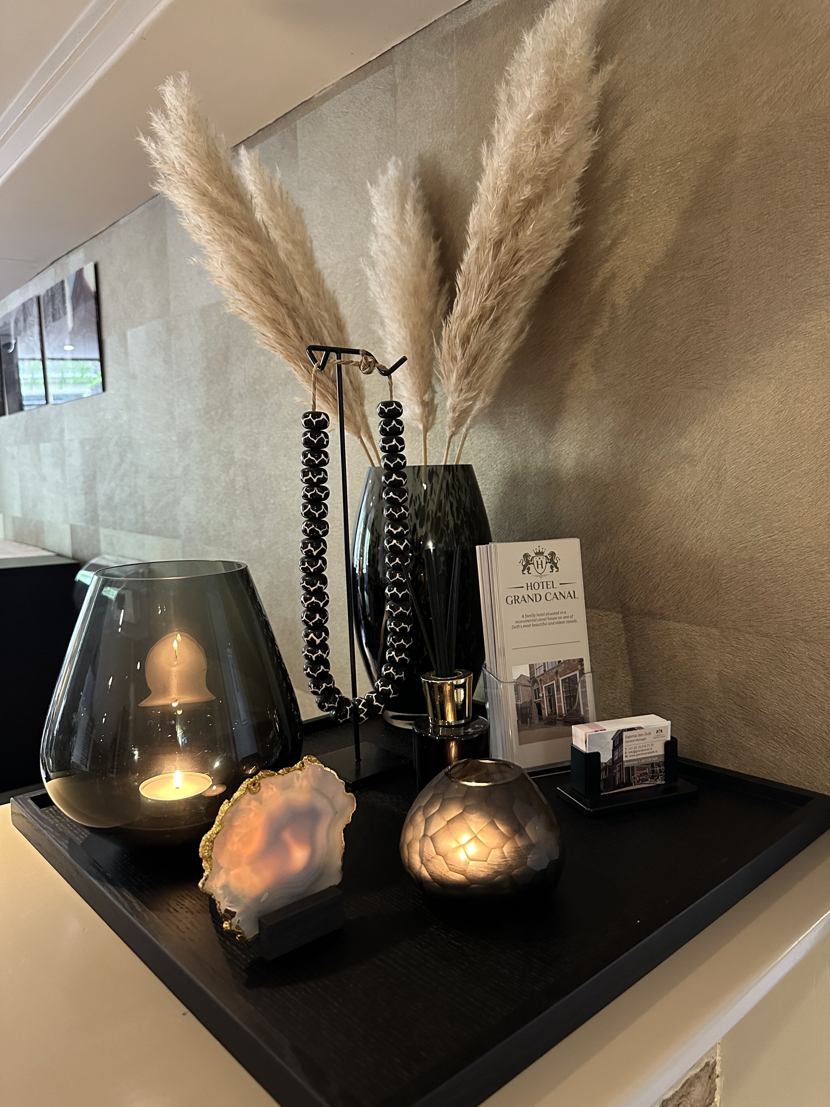 A hotel reception desk with a modern lamp, decorative items, and a brochure.