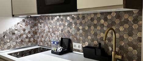 Una cocina con un lavamanos de acero inoxidable, un horno negro y un salpicadero de azulejos hexagonales.