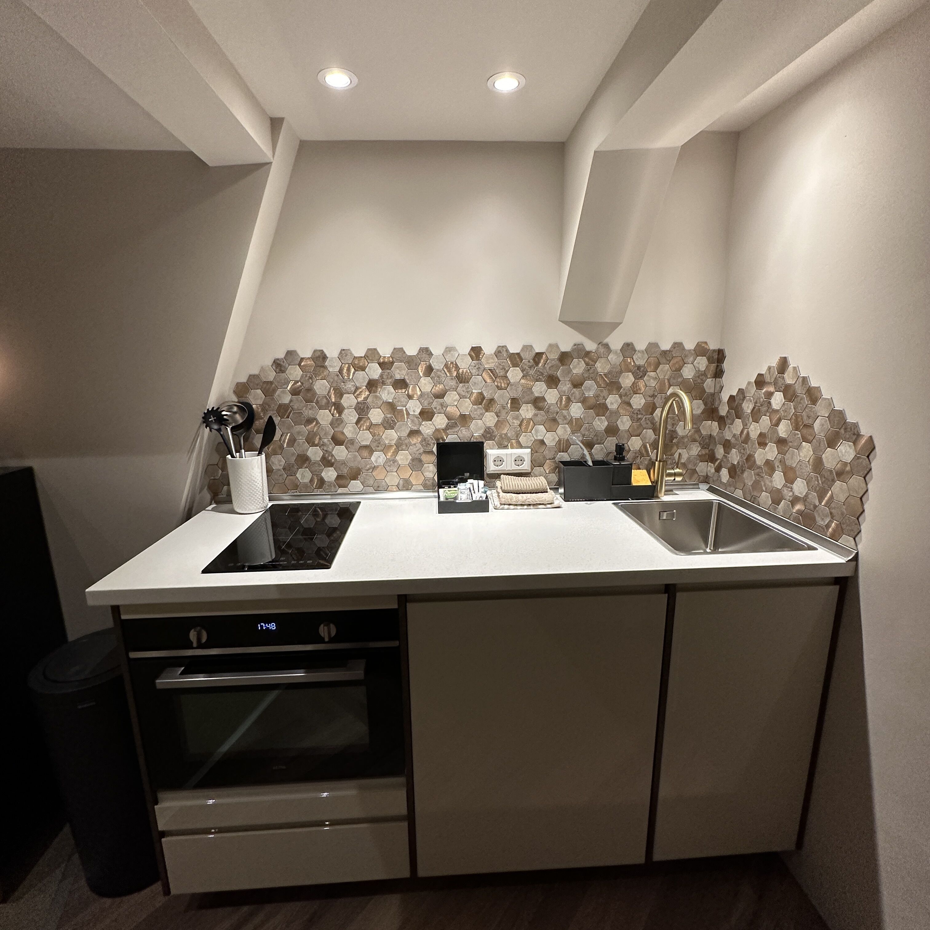 A compact kitchen with a built-in oven, a sink, and a stove.